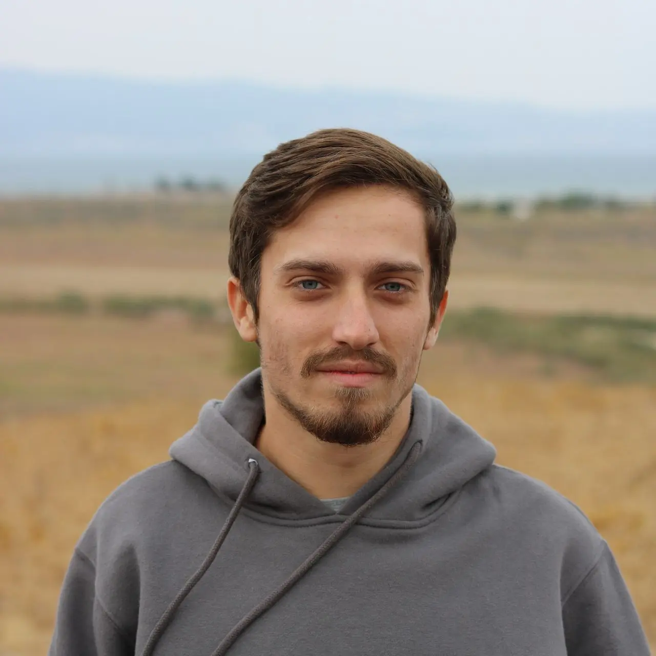 man in gray hoodie standing on field during daytime